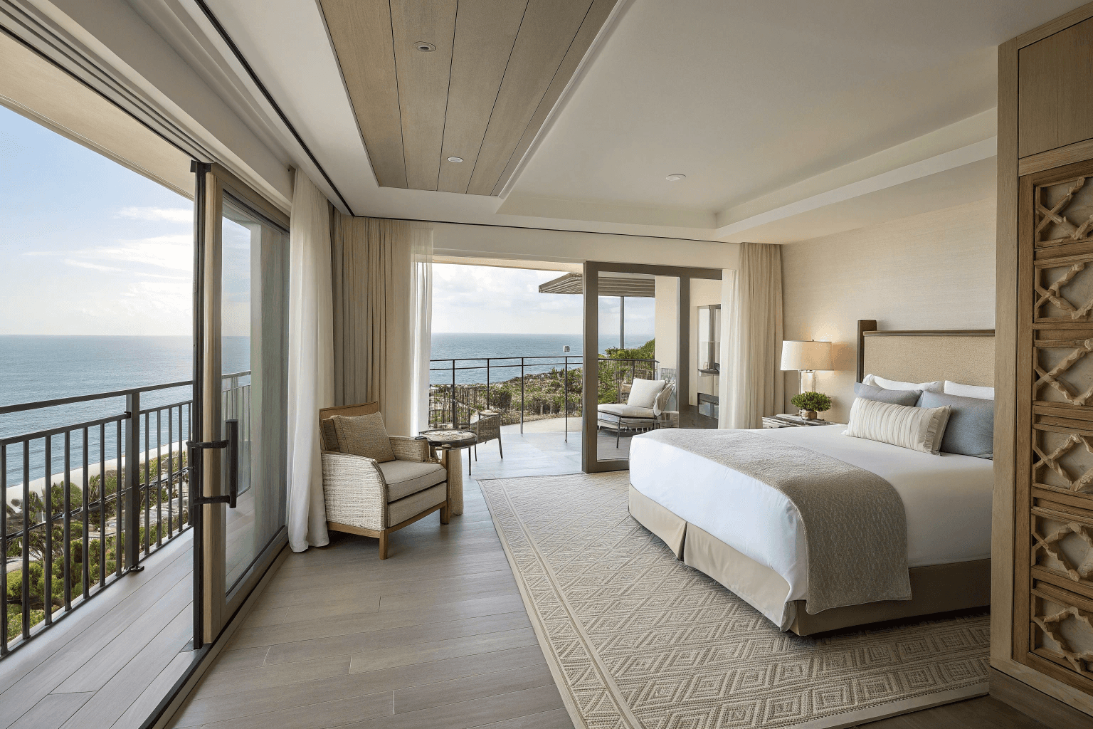 a spacious open-concept layout with a king bed, living area, and ocean beyond full-length windows.