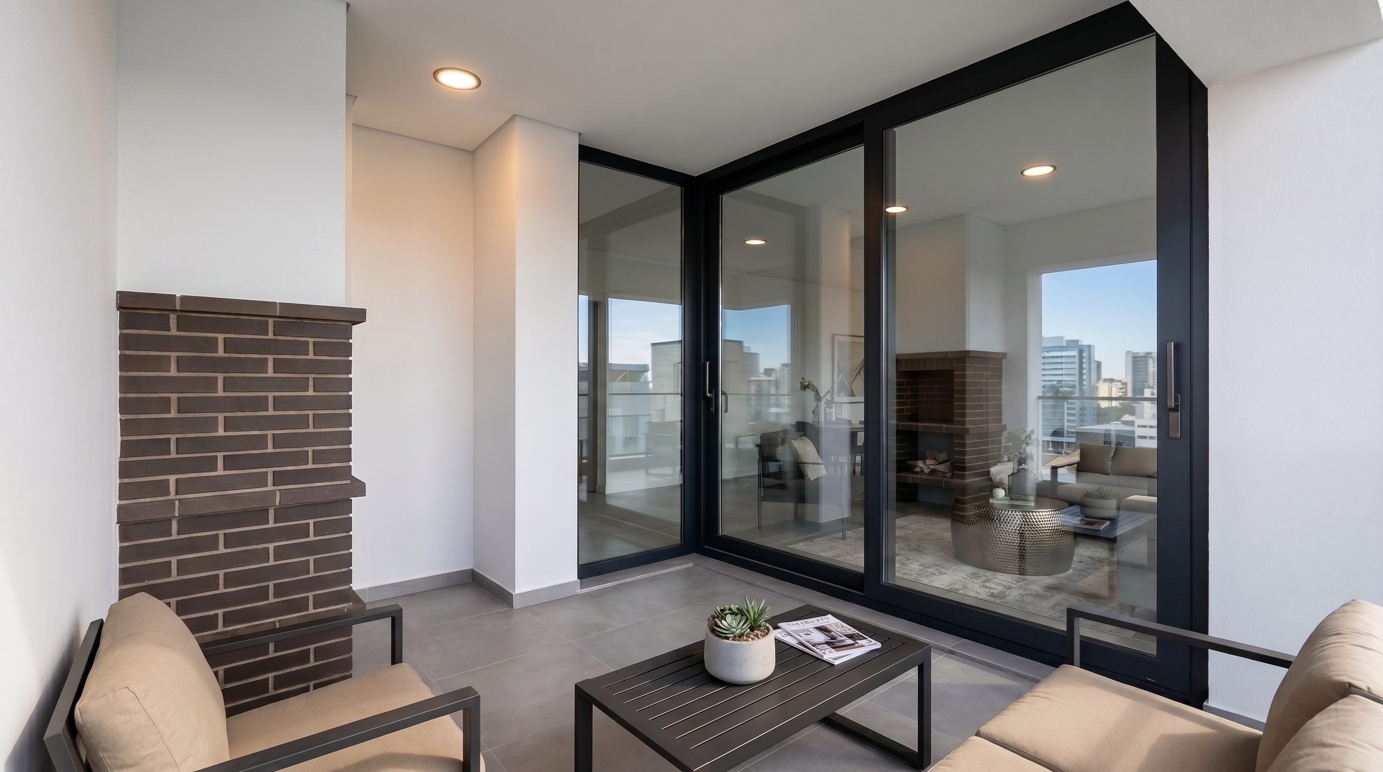A stylish split-level loft room with an elevated queen bed, modern writing desk below, and floor-to-ceiling windows framing a glowing sunset.
